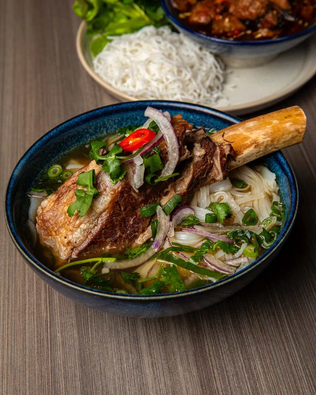 Bowl of 24-hour phở topped with a bone-in beef rib at ĂN ĐI Docklands