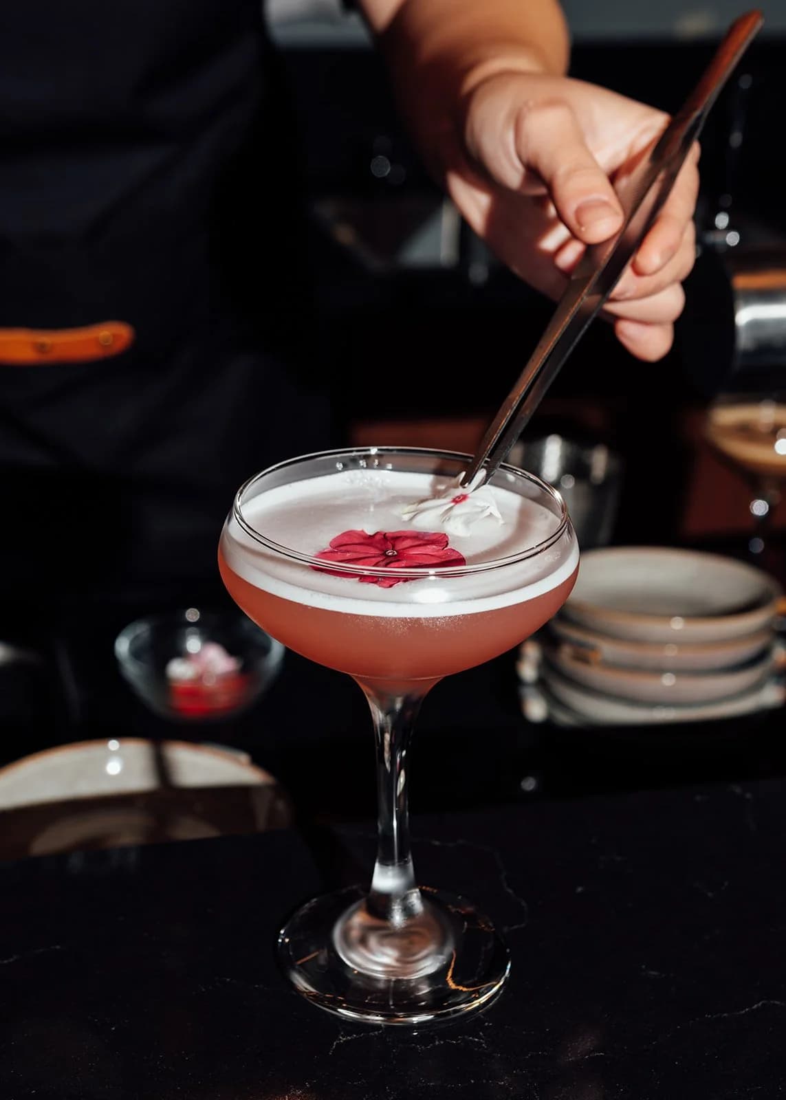 Bartender garnishing a cocktail at the bar of ĂN ĐI restaurant in Docklands
